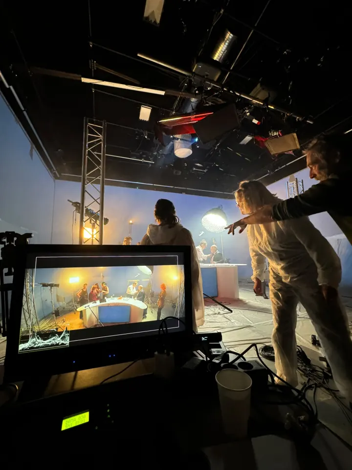 Sur le plateau : un retour vidéo au premier plan, l'équipe règle la scène derrière