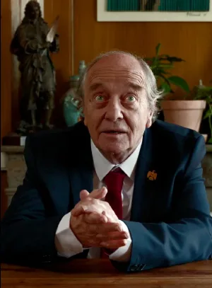 Michel Napalm, assis à son bureau, les mains jointes